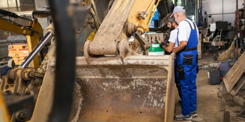 Heavy equipment mechanic performing bucket and boom repair