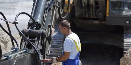 Technician inspecting hydraulic lines on a heavy excavator