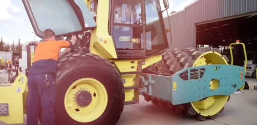Mechanic servicing an Ammann soil compactor / roller in the field